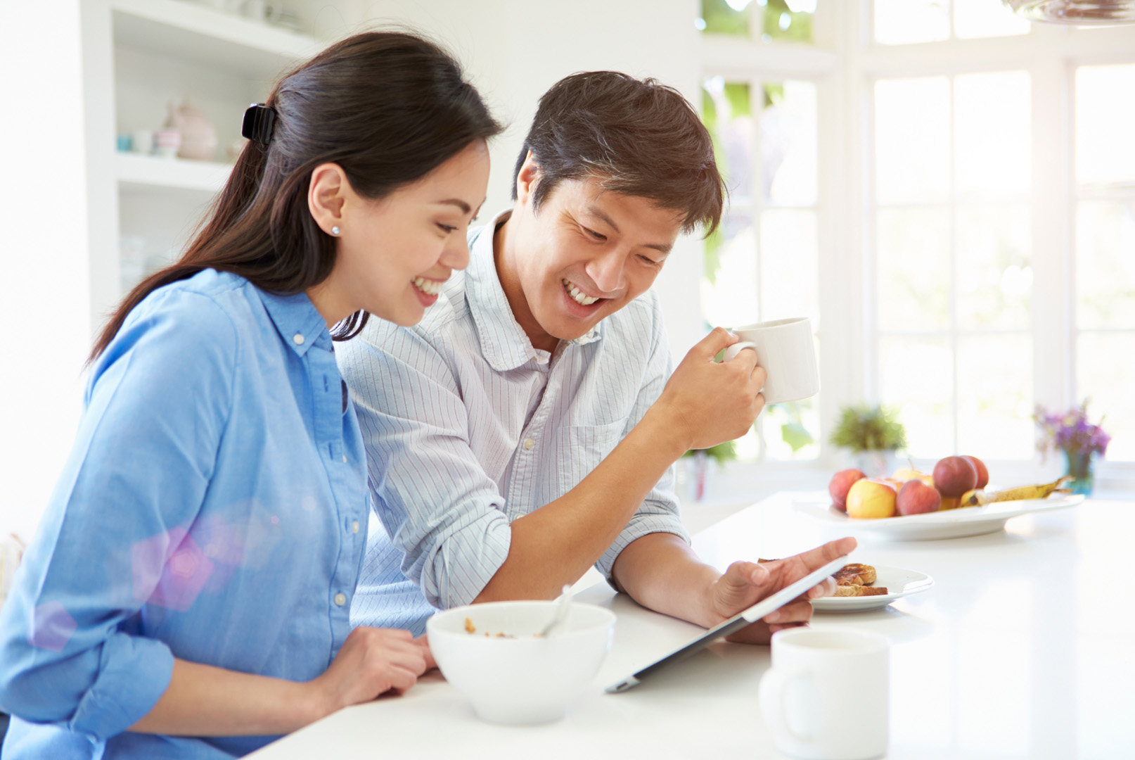 couple in kitchen smiling looking at tablet